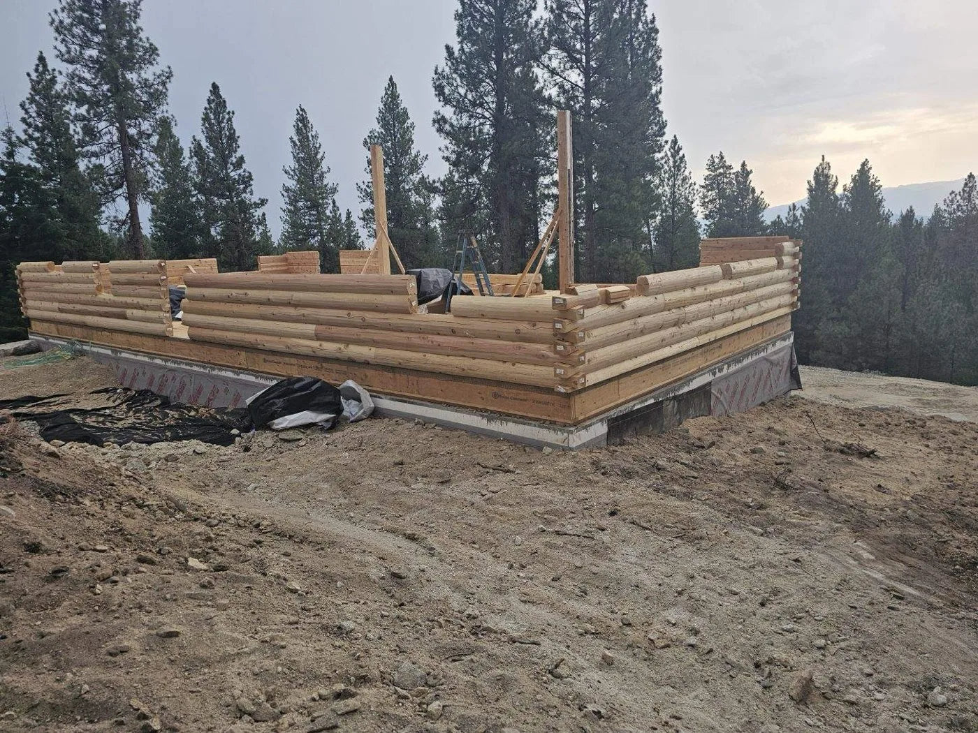 Aerial drone view of a log home foundation and framing lumber staged on site