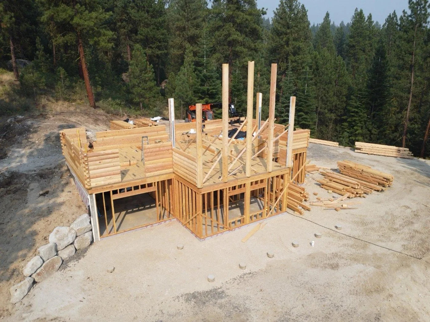 Finished cedar log home at sunset with metal roof and mountain silhouette in the distance