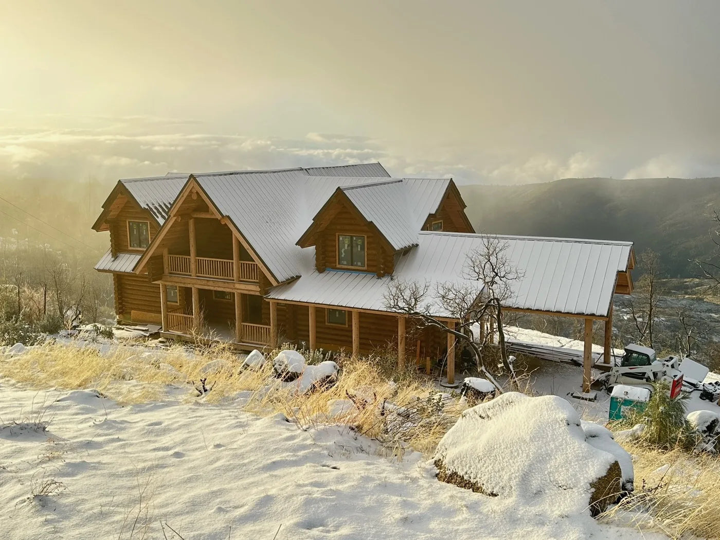 Worker raising log walls on a hilltop build site with a sweeping valley view