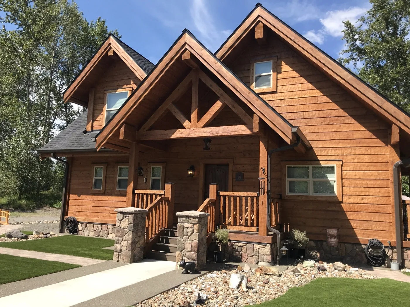 Finished log home entrance with covered porch and stone-clad columns
