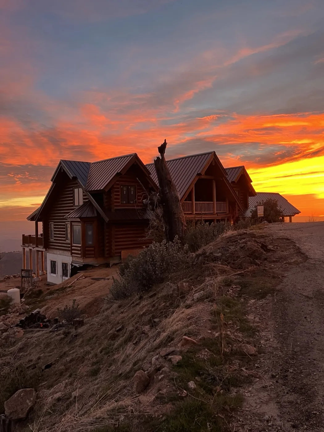 Log home exterior at sunset viewed from a hilltop overlooking the valley