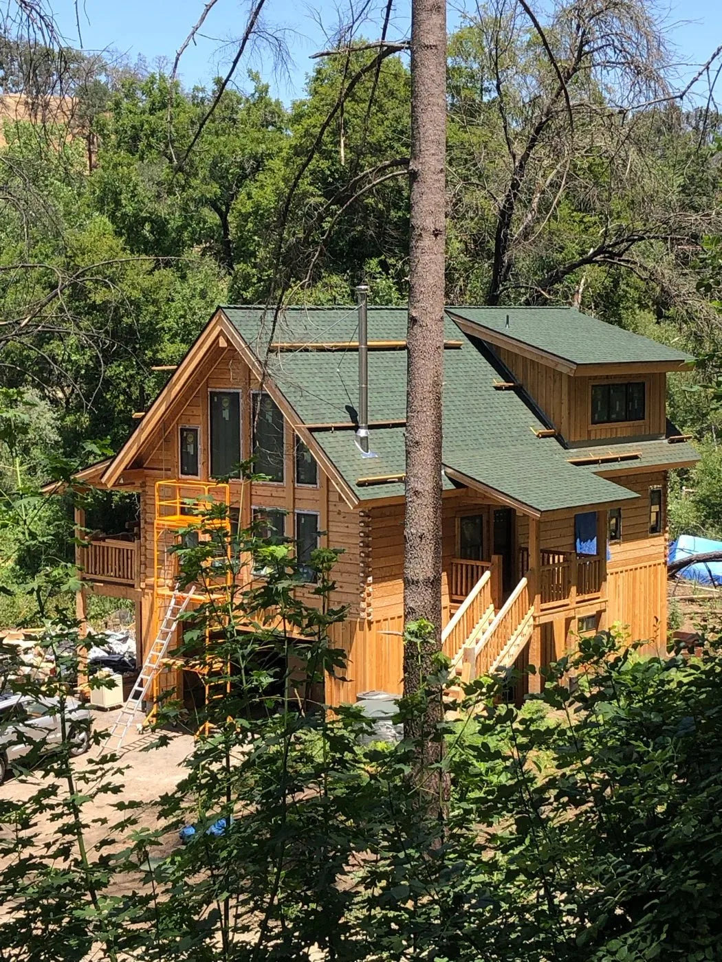 Finished cedar log home exterior with green metal roof and covered porch