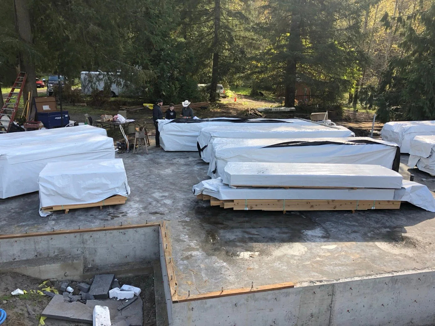 Log package materials wrapped and staged on a concrete foundation slab