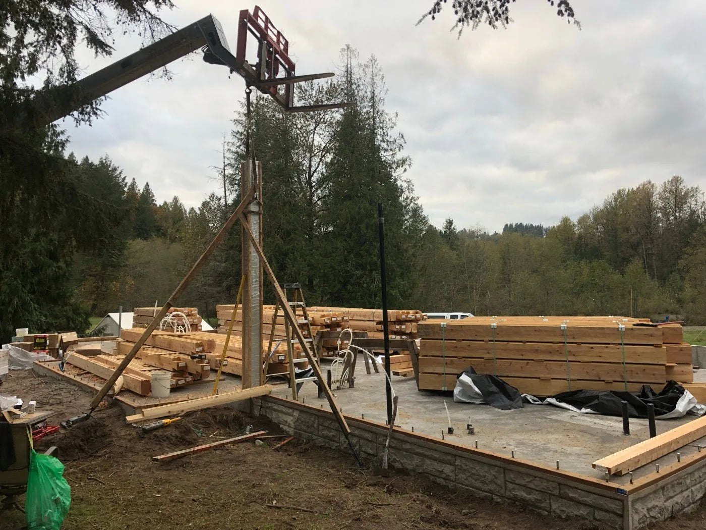 Crane lifting cedar log timbers onto the foundation during log home assembly