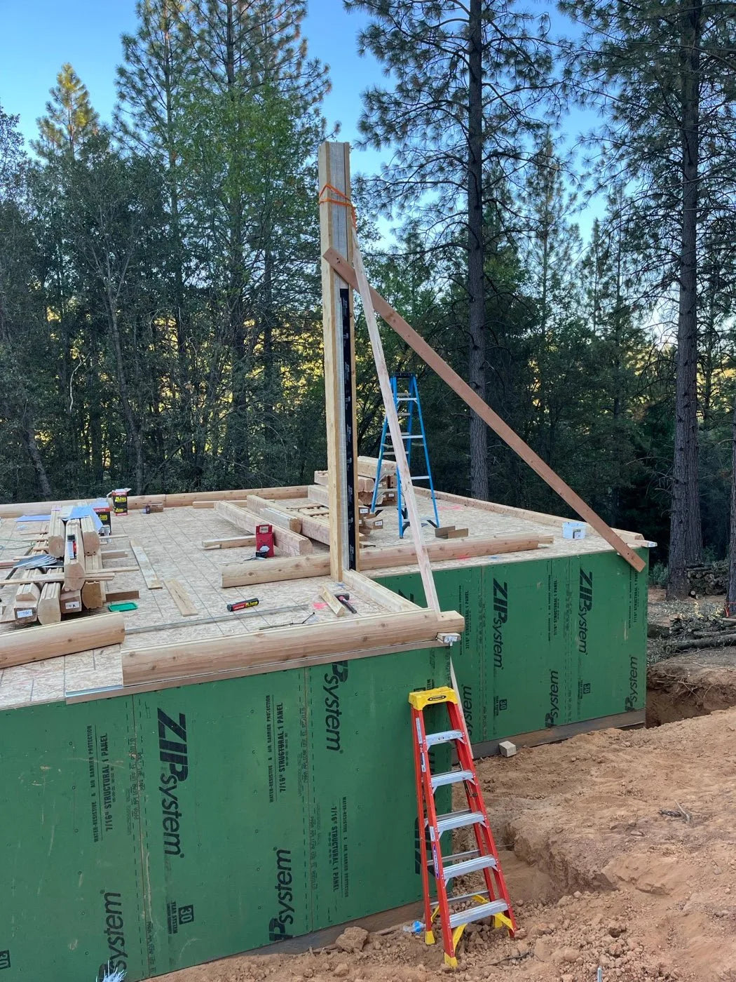 Log home under construction with ZIP System sheathing and a new log post being set