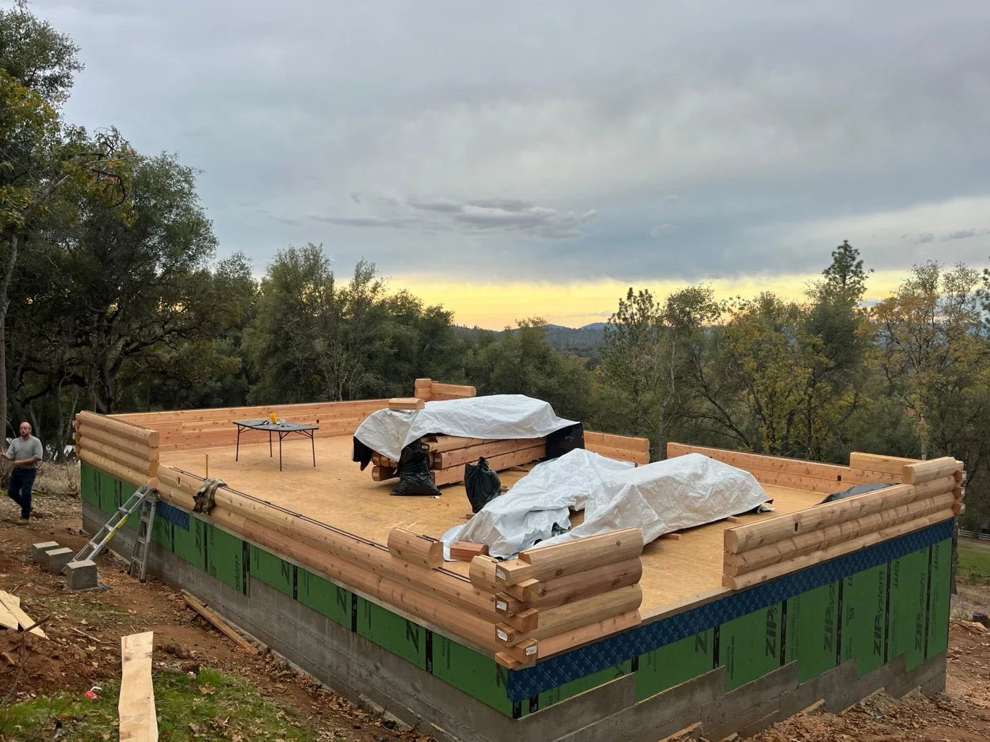 Log home roof deck at dusk with framing lumber staged for the next phase
