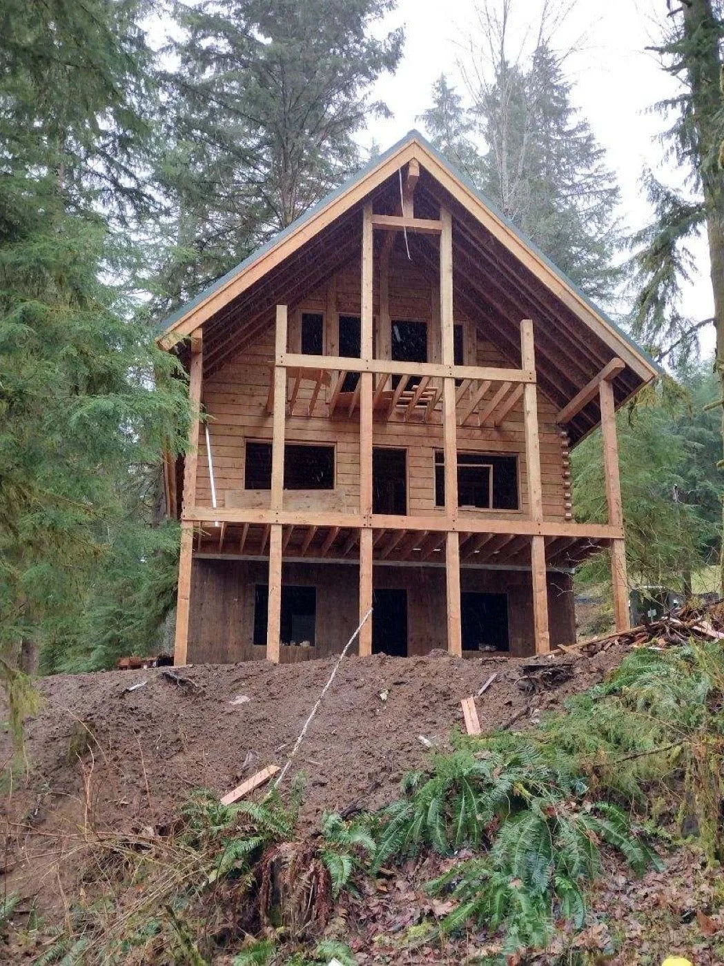 Three-story log home front elevation with large window wall and covered deck