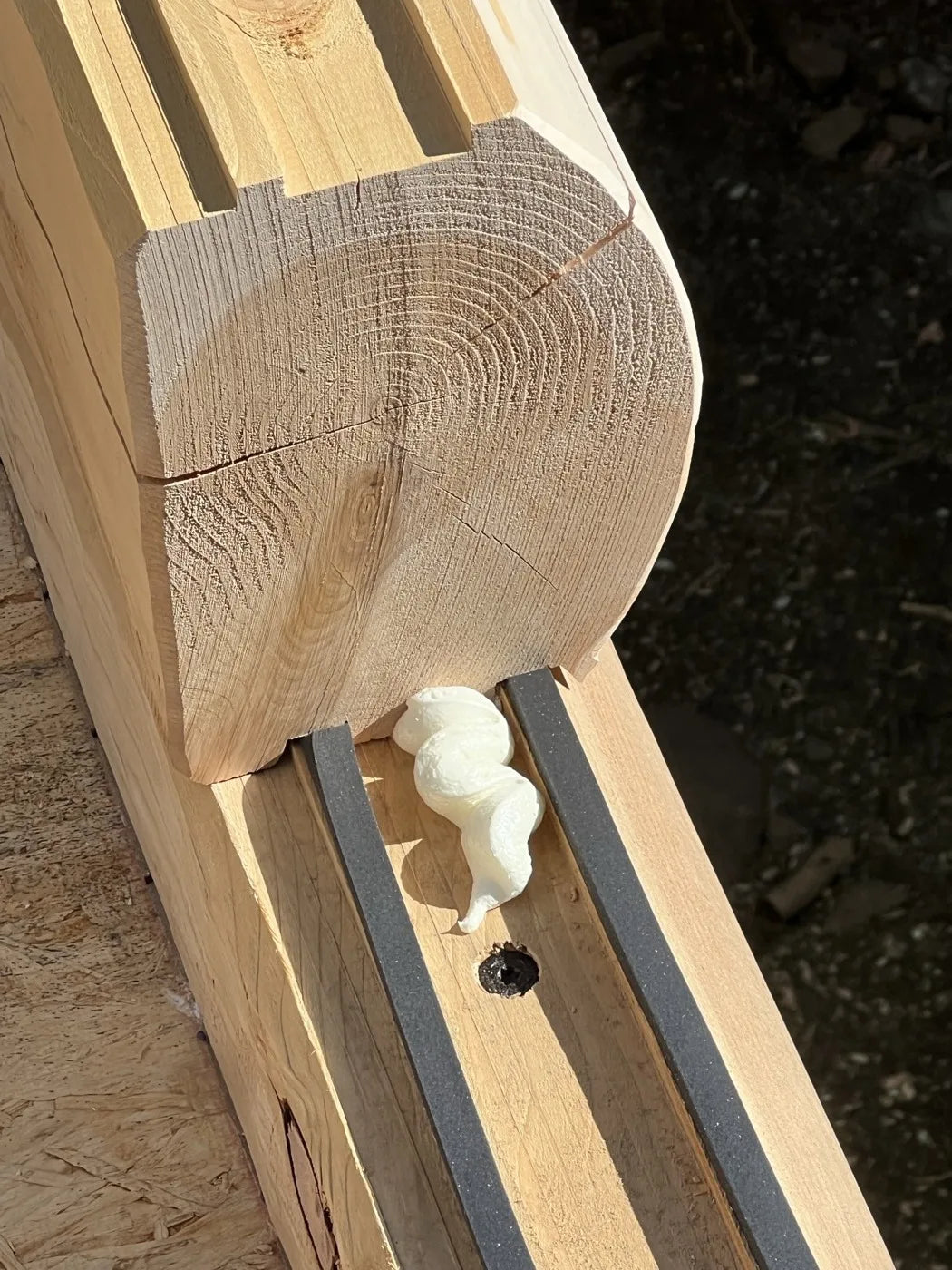 Close-up of a squared cedar timber corner joint with foam sealant