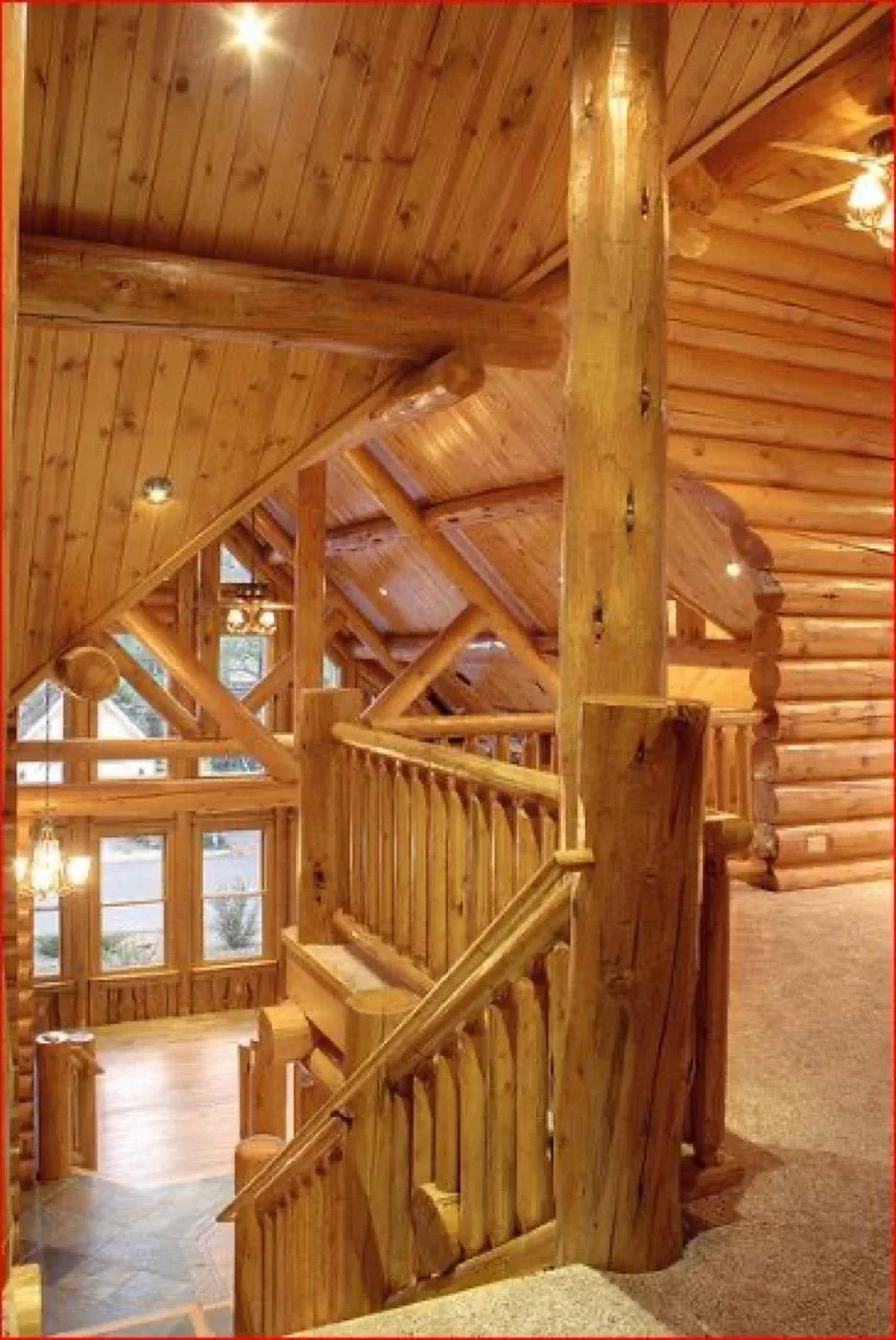 Great room interior with stone fireplace, log trusses, and mounted moose antlers