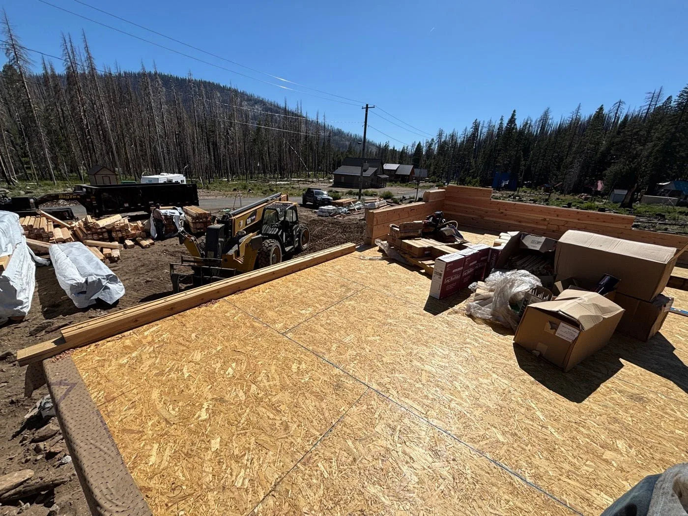Log home roof framing under construction with materials staged on the deck