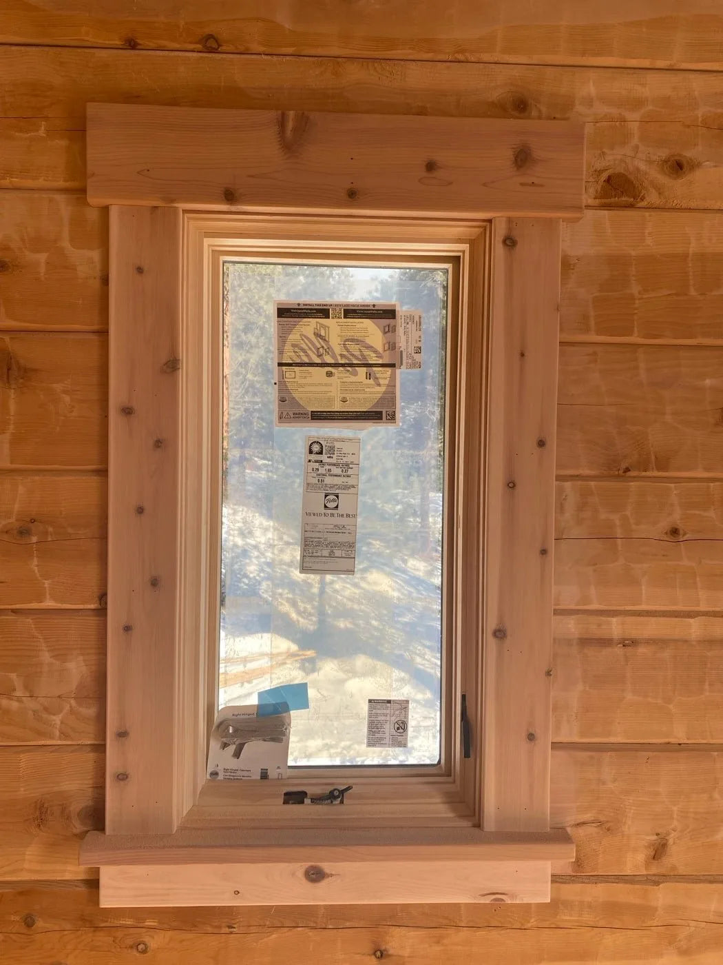 Close-up of a custom cedar window casing being installed with manufacturer tags still attached