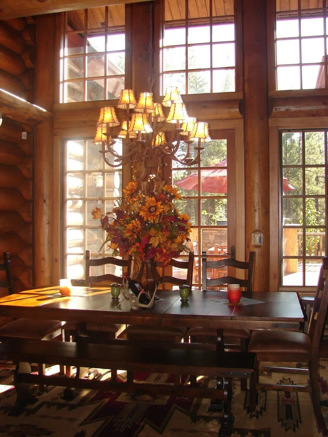 Two-story log home great room with tall arched windows and a fall floral centerpiece