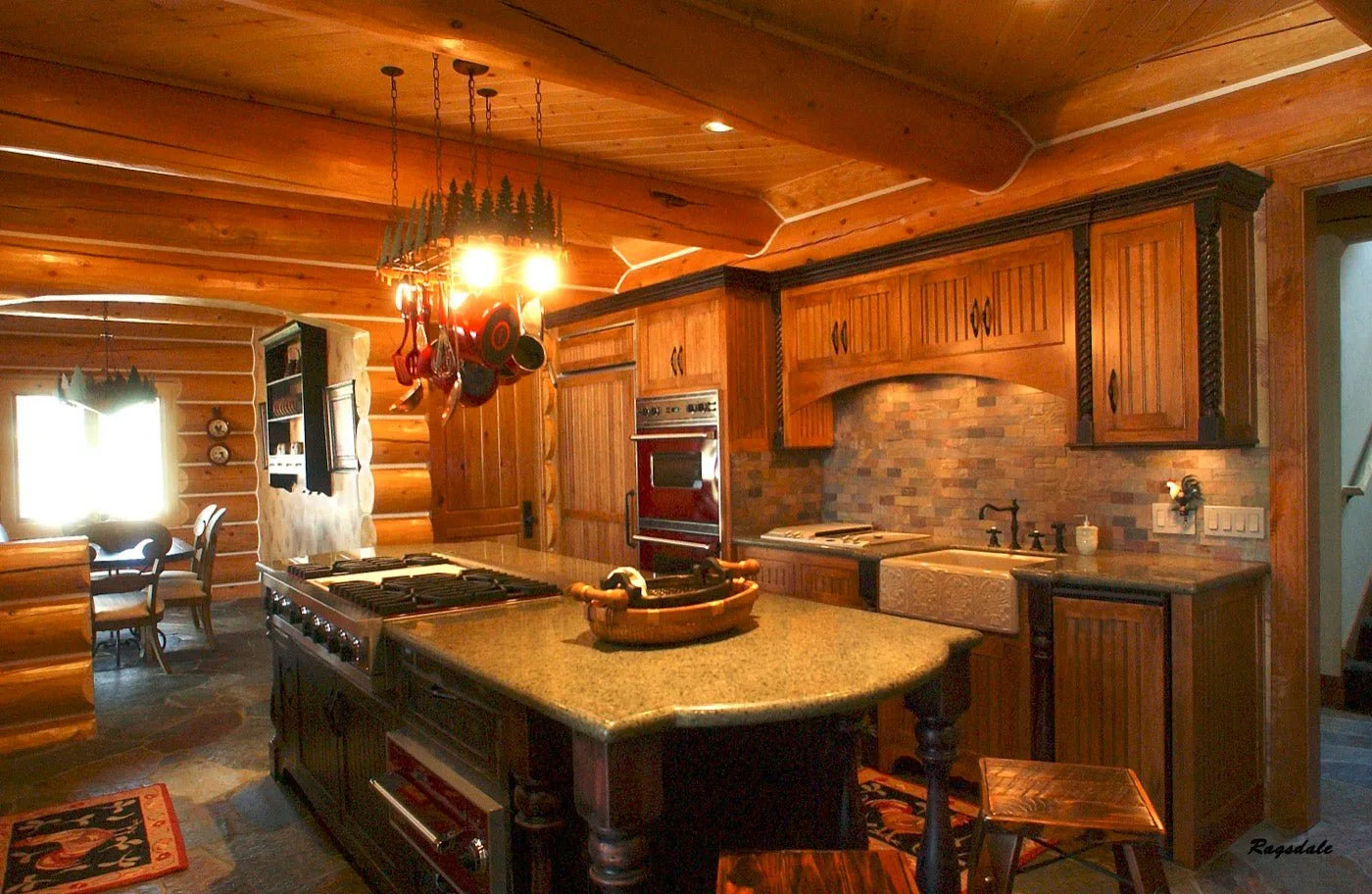 Log home kitchen with a granite island, custom range hood, and stone tile backsplash
