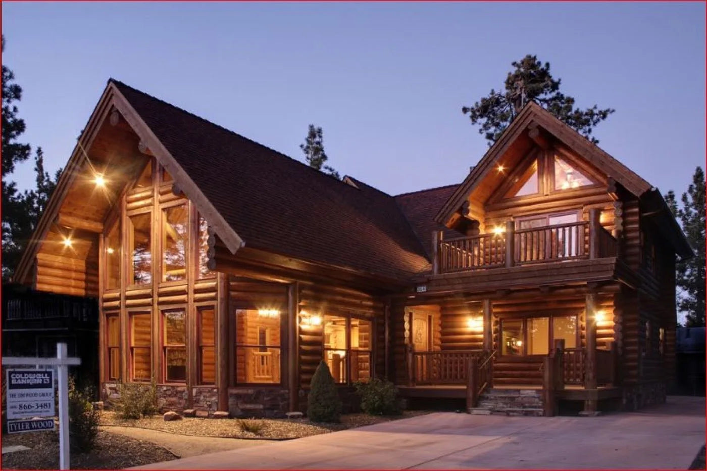 Two-story log home exterior at dusk with warmly lit windows and a covered entry