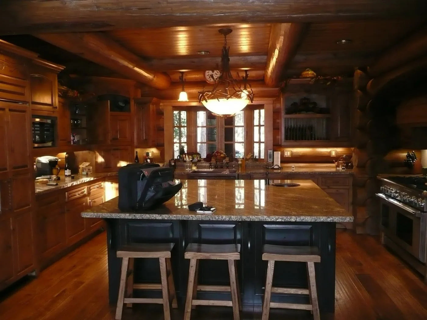 Log home kitchen island with a granite countertop, dark cabinetry, and wood bar stools